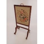 An early 19th century rosewood firescreen with vertical sliding tapestry panel, all on twin scroll