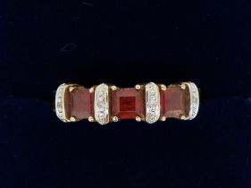 A 9 carat gold ring set orange stones and bands of chip diamonds, size O, 2.9g