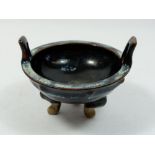A Yuan dynasty black glazed Bazhou kiln two handled bowl on triple feet, 12.5cm diameter