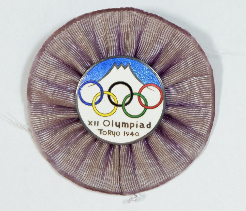 A rare Olympiad Officials enamel badge with purple rosette surround, from the Tokyo cancelled
