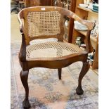 An early 20th century corner caned chair with claw and ball feet