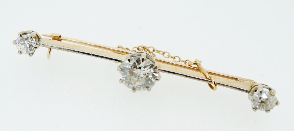 An 18 carat and platinum gold bar brooch set central diamond (1.48cts) flanked by two further