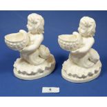 A Victorian pair of porcelain mer children holding shell form salts, 15cm tall
