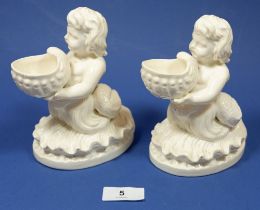 A Victorian pair of porcelain mer children holding shell form salts, 15cm tall