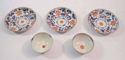 Two oriental tea bowls and three saucers painted iron red flowers and blue scrolling stems