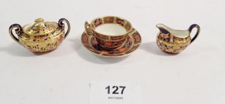 A Royal Crown Derby miniature covered sugar bowl, jug and teacup, 3cm tall
