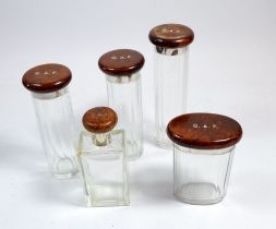 A set of five glass gentleman's toiletry bottles with silver and burr walnut lids, London 1935,