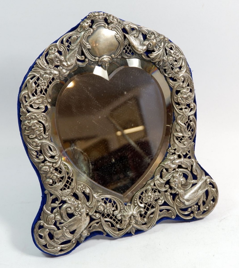 A Victorian silver heart form easel mirror pierced with birds, masks and foliate decoration,
