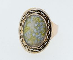 A George III gold mourning ring with enamel oval surround to encapsulated embroidered fabric (