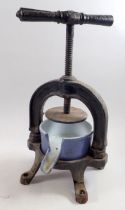 A cast iron fruit press with blue enamelled iron bowl