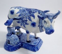 A Faience blue and white cow and milkmaid, marked KB, 17.5cm tall