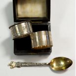 A silver napkin ring and a plated one and a napkin ring box plus a silver spoon