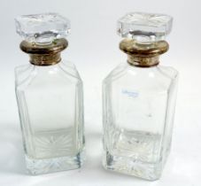 A pair of glass decanters with silver rims