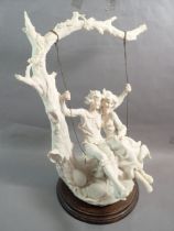 A large Capodimonte bisque figure of a couple on a swing, 43cm tall