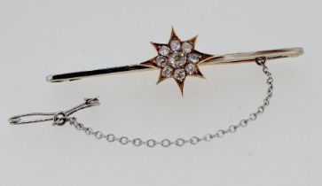 An antique 18 carat and 15 carat white and yellow gold bar brooch with diamond set star and safety
