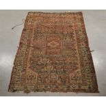 A worn early 20th century middle eastern rug, wool on wool, retailed by Harvey Nichols, label to the