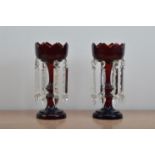 A pair of turn of the century cranberry glass lustres, with worn heightened gilt work, later glass