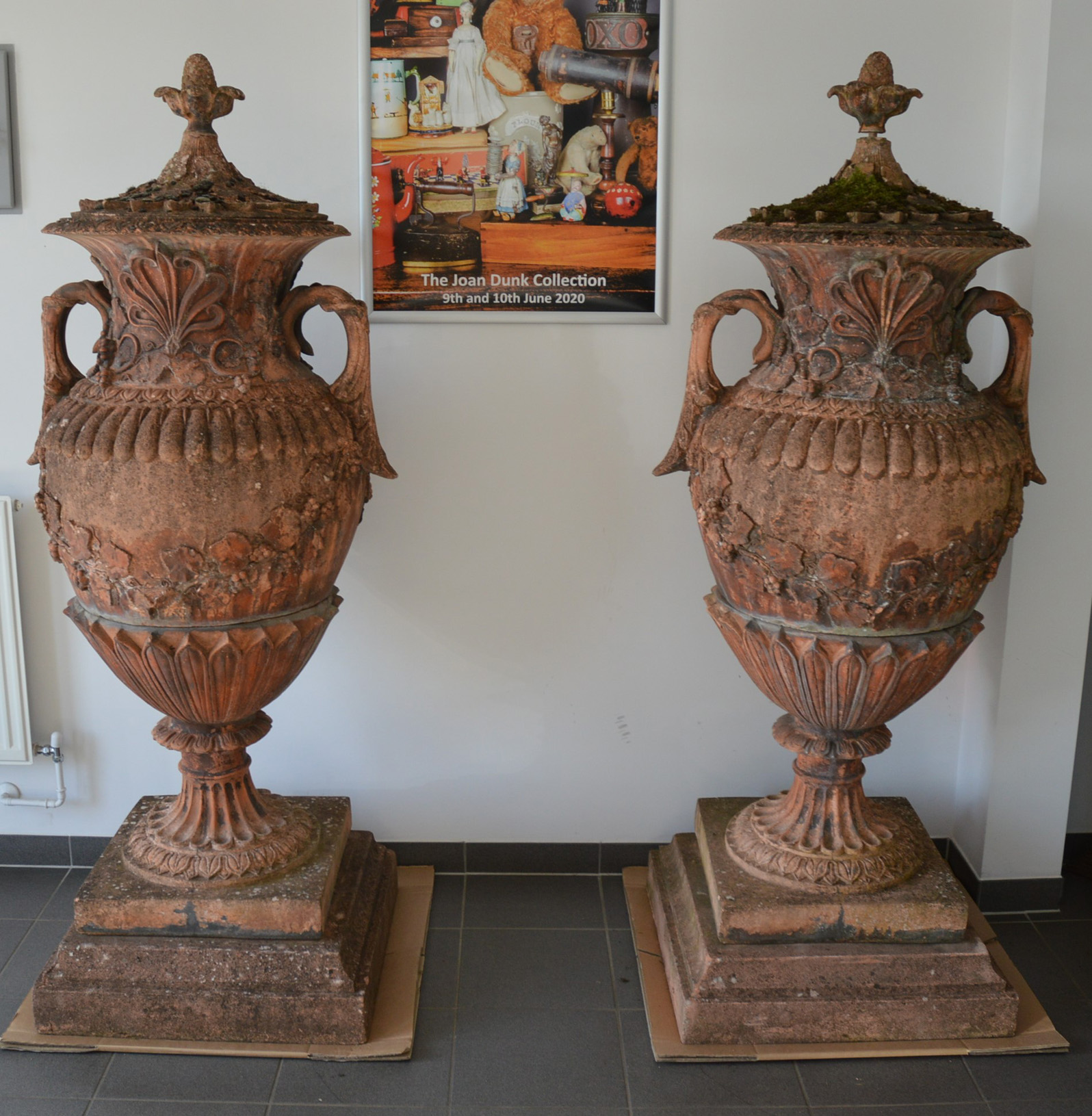 A pair of large and impressive stone covered garden urns, terracotta colour, the covers with