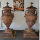 A pair of large and impressive stone covered garden urns, terracotta colour, the covers with