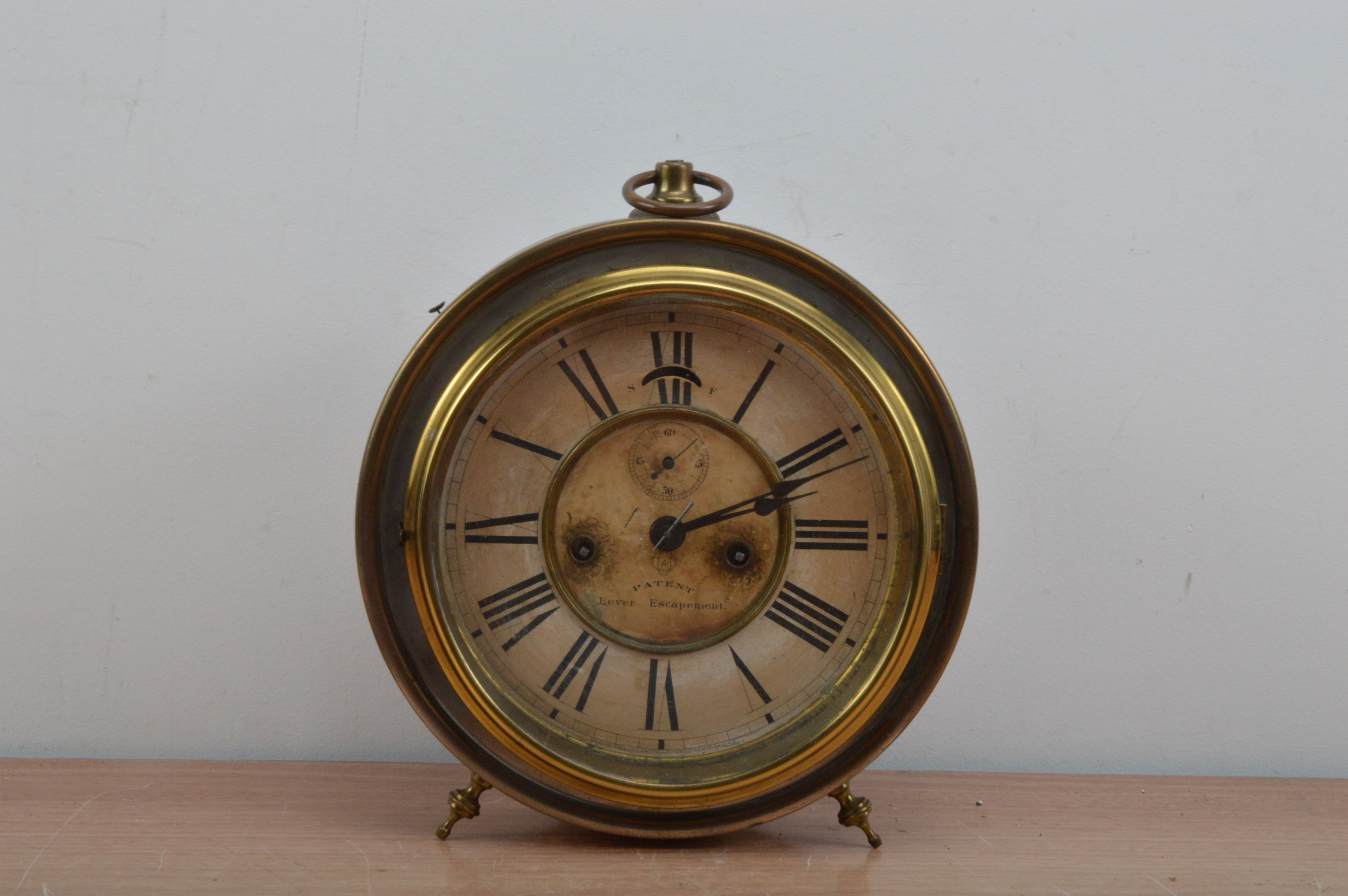 An Ansonia Clock Company American copper and brass circular clock, raised on two feet with a