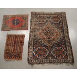 Three woollen rugs, the largest worn, with a geometric design, 136cm x 93cm, together with a small