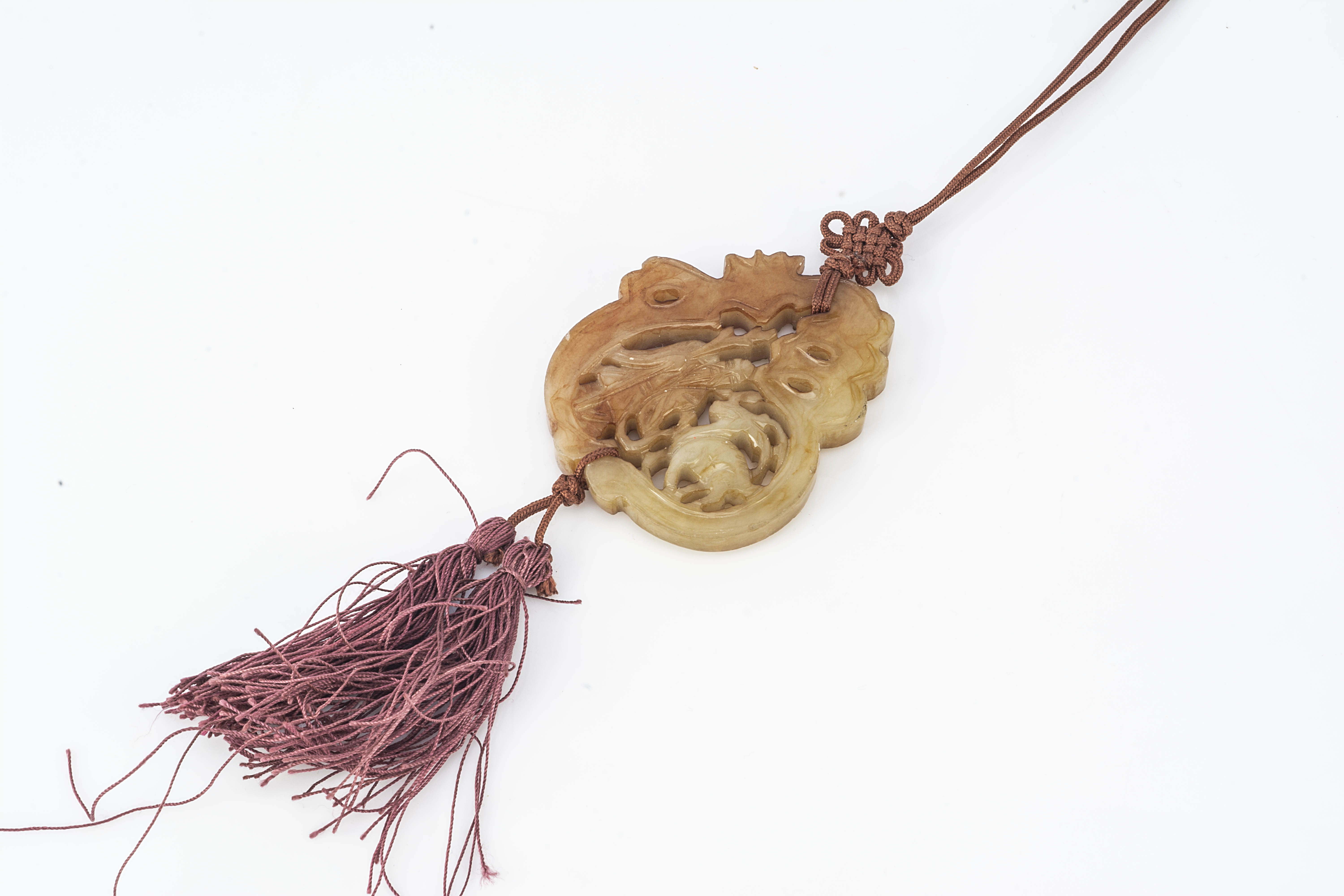 A Chinese hardstone panel pendant, with pierced form of elder and goat, on a burgundy silk cord with