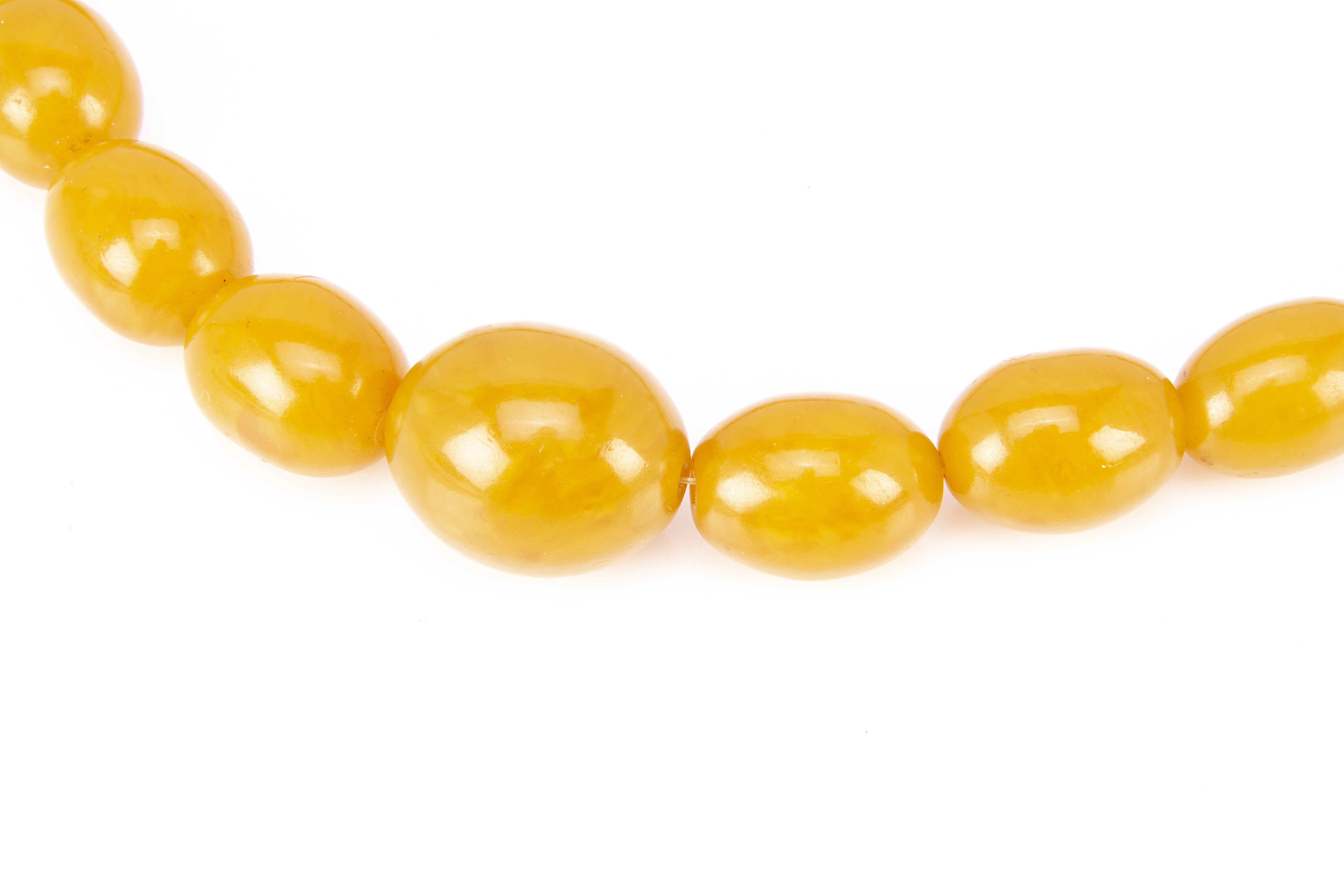 A string of graduated pressed amber oval beads, largest 2.5cm, smallest 1.8cm, 30.5cm together, 94g - Image 2 of 2