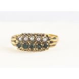 A 19th Century 15ct emerald and seed pearl ring, the two pairs of parallel set gems in scroll