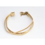 A continental 18ct gold three strand bracelet, with snap collar and tassels marked 750, 23 cm by 1.5