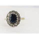 An 18ct gold sapphire and diamond cluster ring, the dark blue mixed oval cut sapphire surrounded