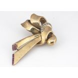 An Art Deco 9ct gold ruby and diamond bow clip brooch, the double pin in hinged white metal
