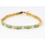 A 14ct gold emerald and diamond line bracelet, the pairs of channel set emeralds alternately set