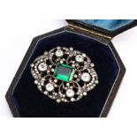 A 19th Century silver oval openwork paste set brooch, with central rectangular green cut gem, within