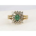 An 18ct gold emerald and diamond cluster ring, the claw set emerald surrounded by two bands of