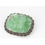 A Chinese jadeite jade carved oval panel brooch, in white metal filigree setting, the carved panel