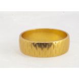 A 22ct gold wedding band, of flattened form with textured shank, ring size M1/2, 6 mm wide, 5.7g