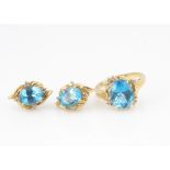 A 14ct gold blue topaz and diamond ring and earring set, the decorative crossover style ring, ring