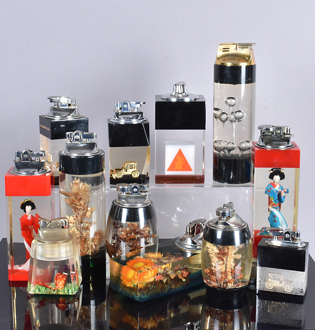 An assortment of resin table lighters, with various designs, including plants, vehicles, geishas and