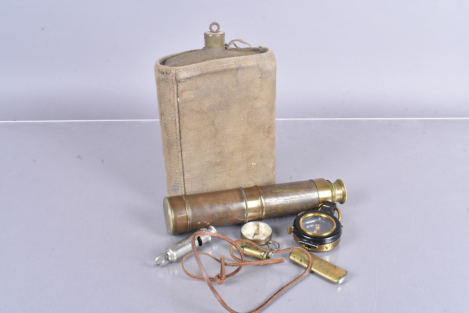 An assortment of military items, including two trench lighters, a 1935 military marked compass, an