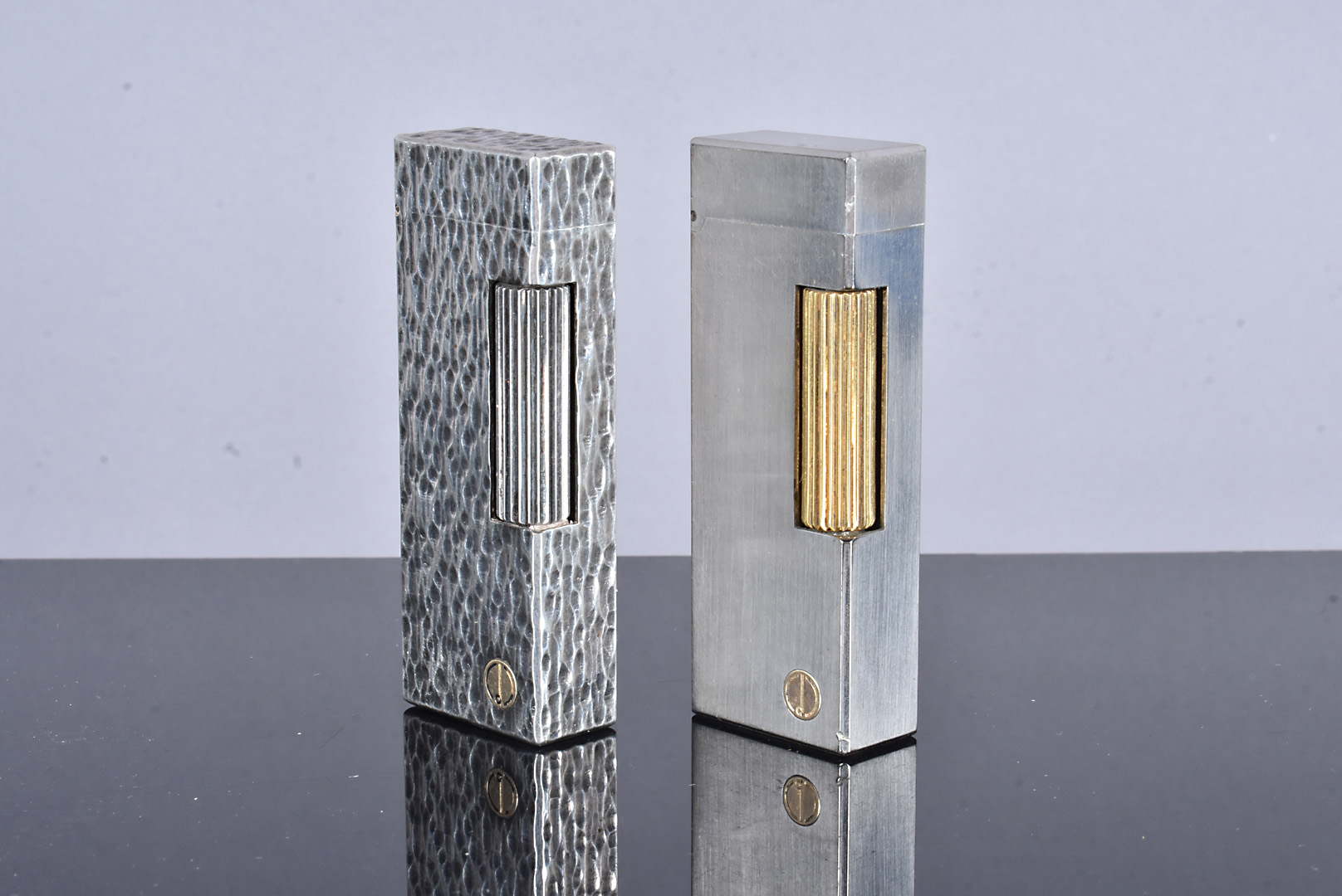 Two Dunhill Rollagas white metal pocket lighters, one with brushed design, the other with a hand