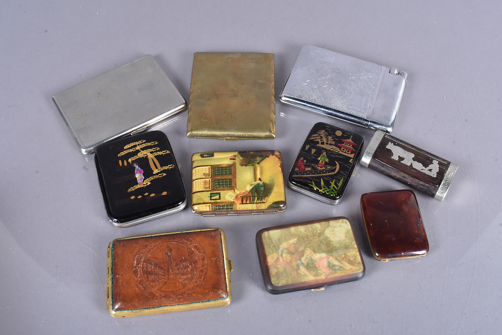 A small collection of cigarette cases, to include a base metal example by Emu, a brass example '