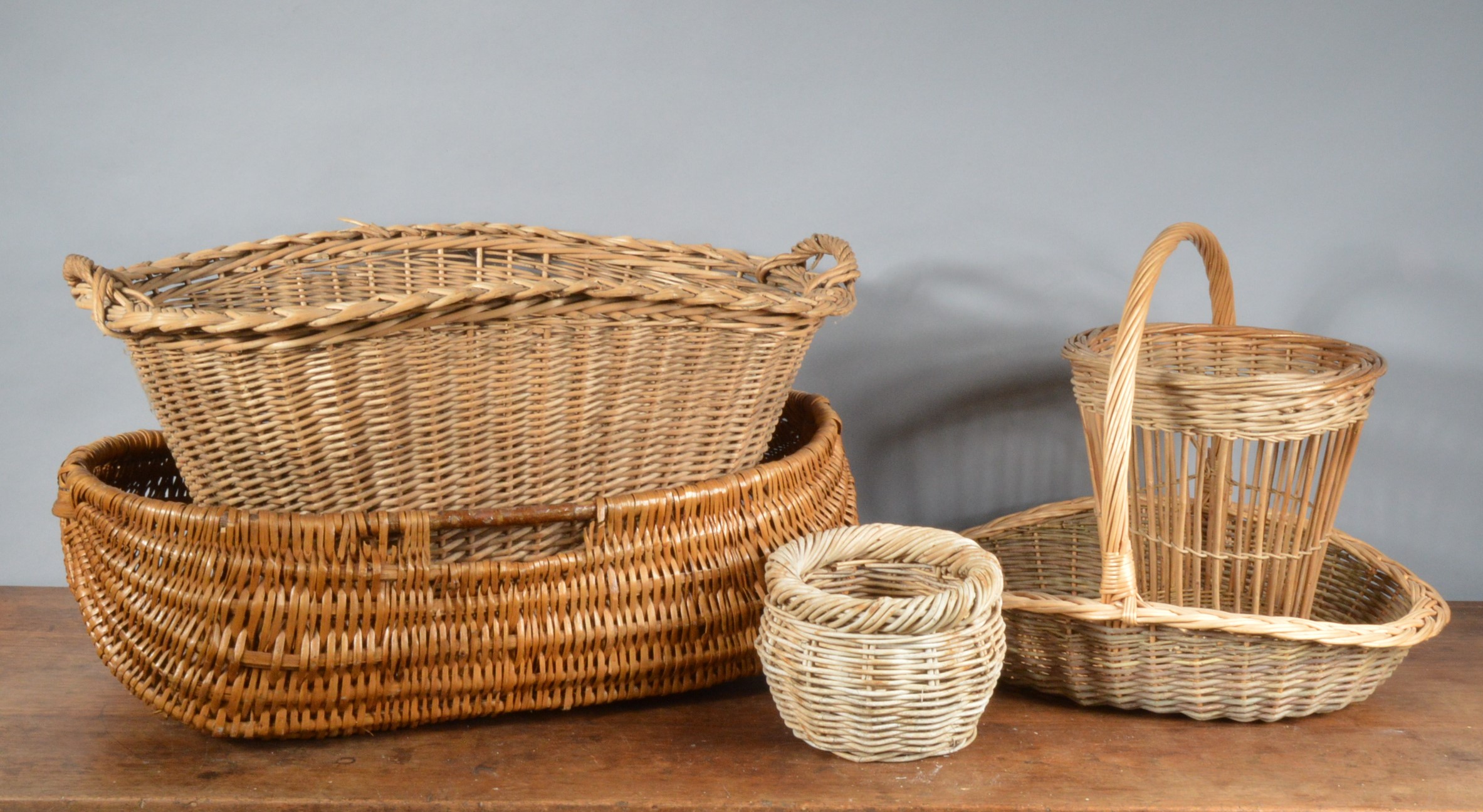 A collection of wicker items, comprising two large twin handled baskets, the largest 73cm in length,