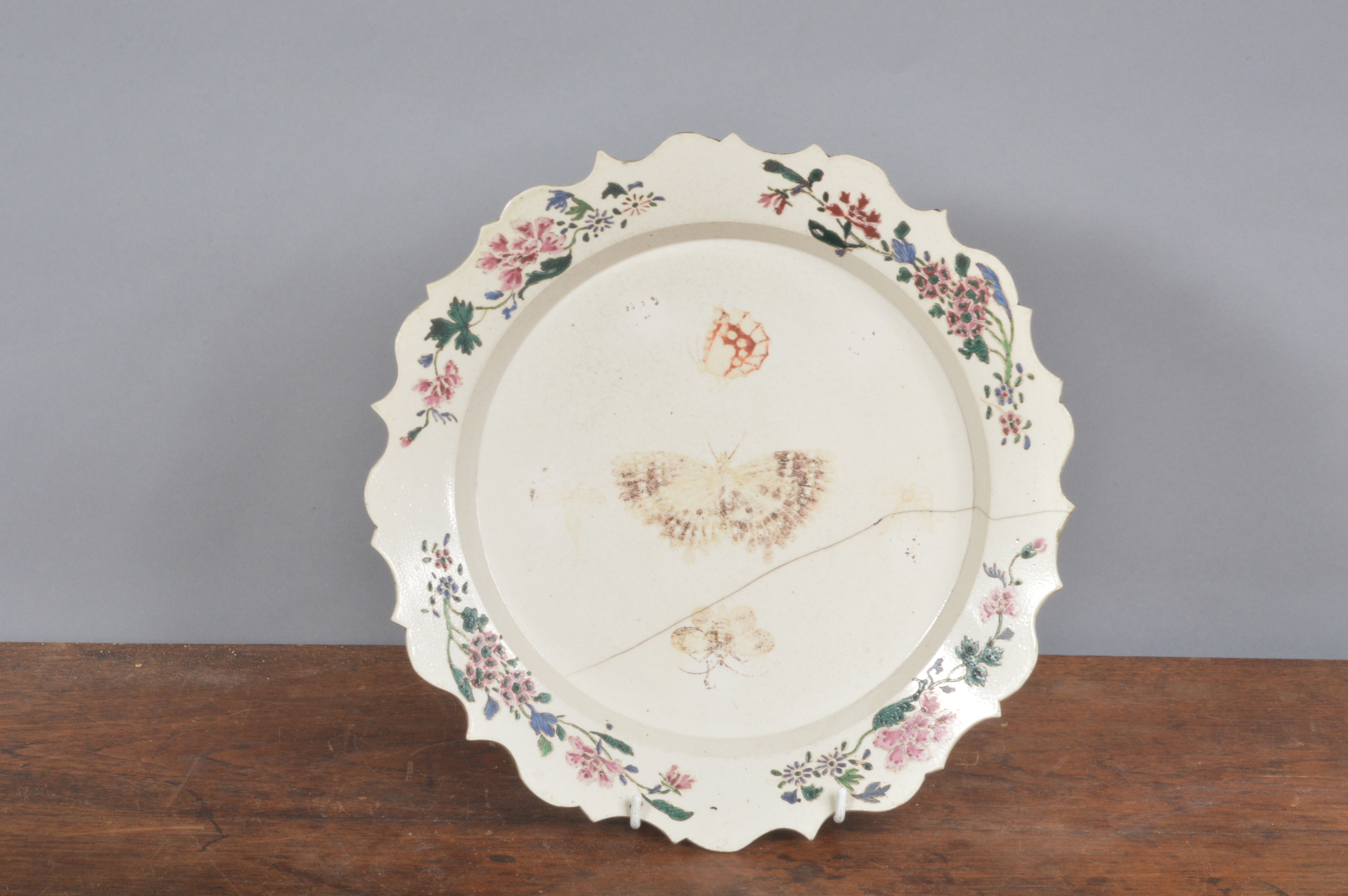 An 18th century salt glazed shaped plate, with painted floral decoration to border and insects and