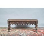 A 19th century and later carved long wooden bench, foliate scroll craving, on turned and carved