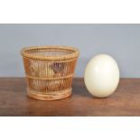 A large collection of eggs, presented in a wicker basket 17.5cm H x 23cm W, to include an ostrich