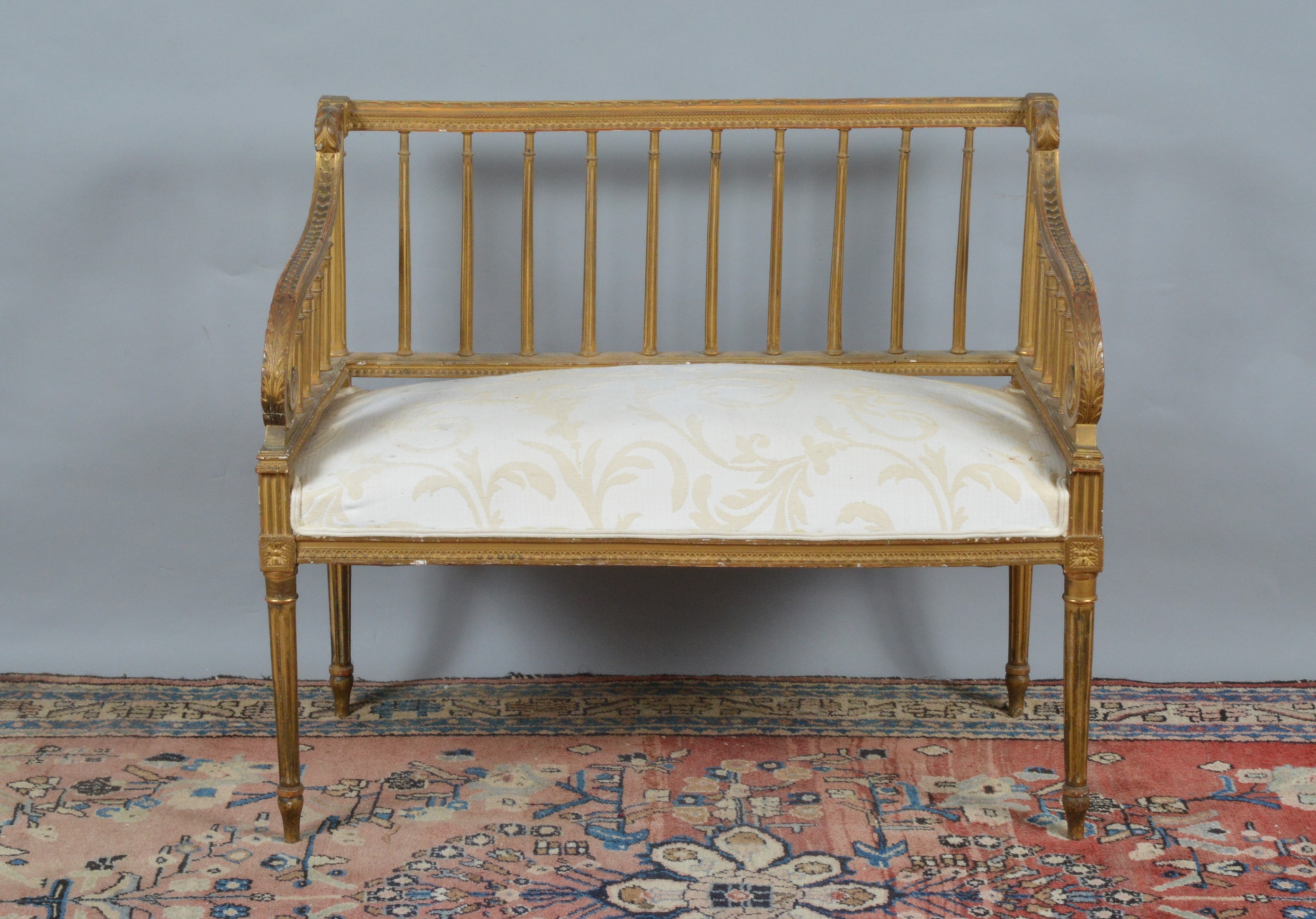 A French giltwood two person settee, fluted column back splat, ornate arms, upholstered seat, raised