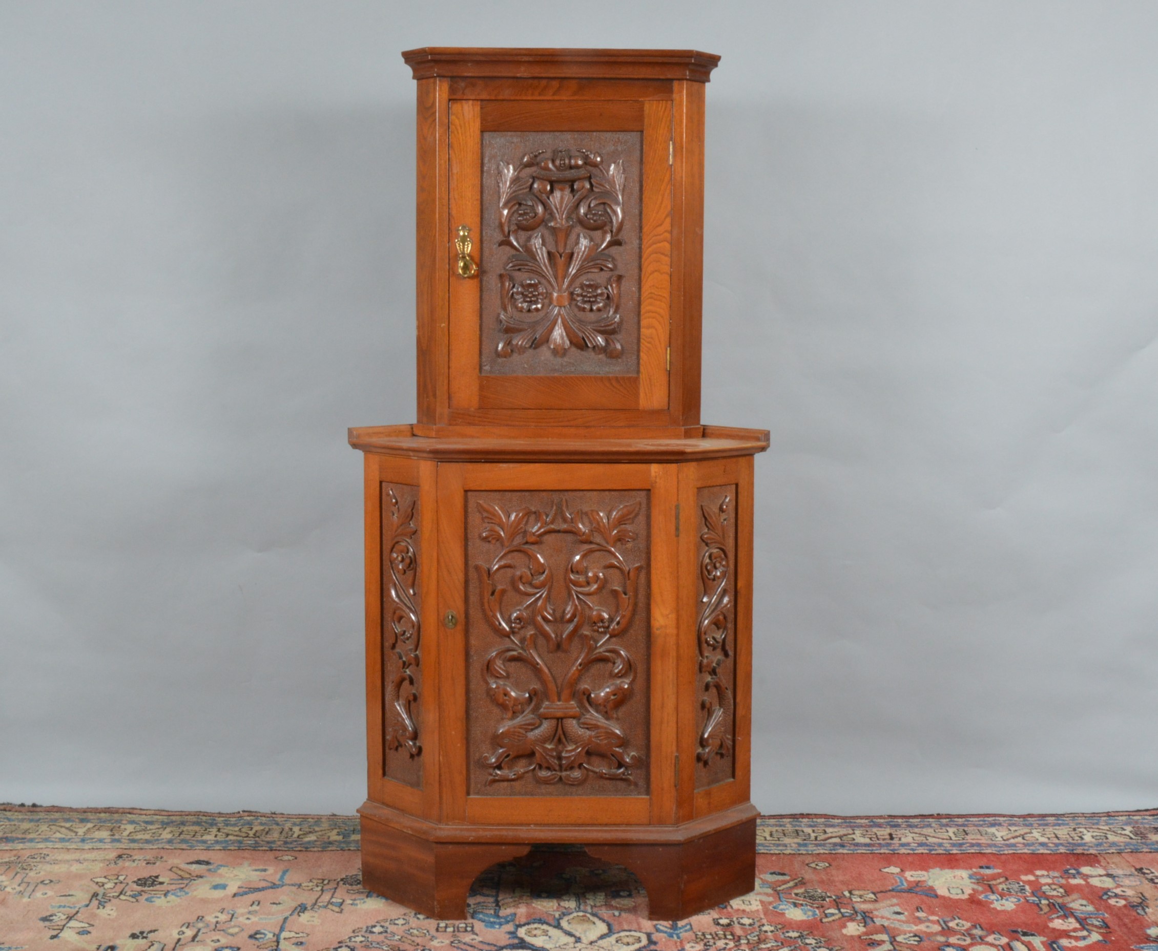A mid to late 20th century oak corner cabinet, with floral carved design, together with a matching