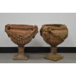 A pair of neoclassical garden urns, possibly terracotta. With horned mask handles and swag