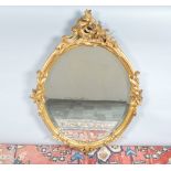 A 19th century and later oval gilt mirror, mounted with a pediment, foliate scroll decoration,