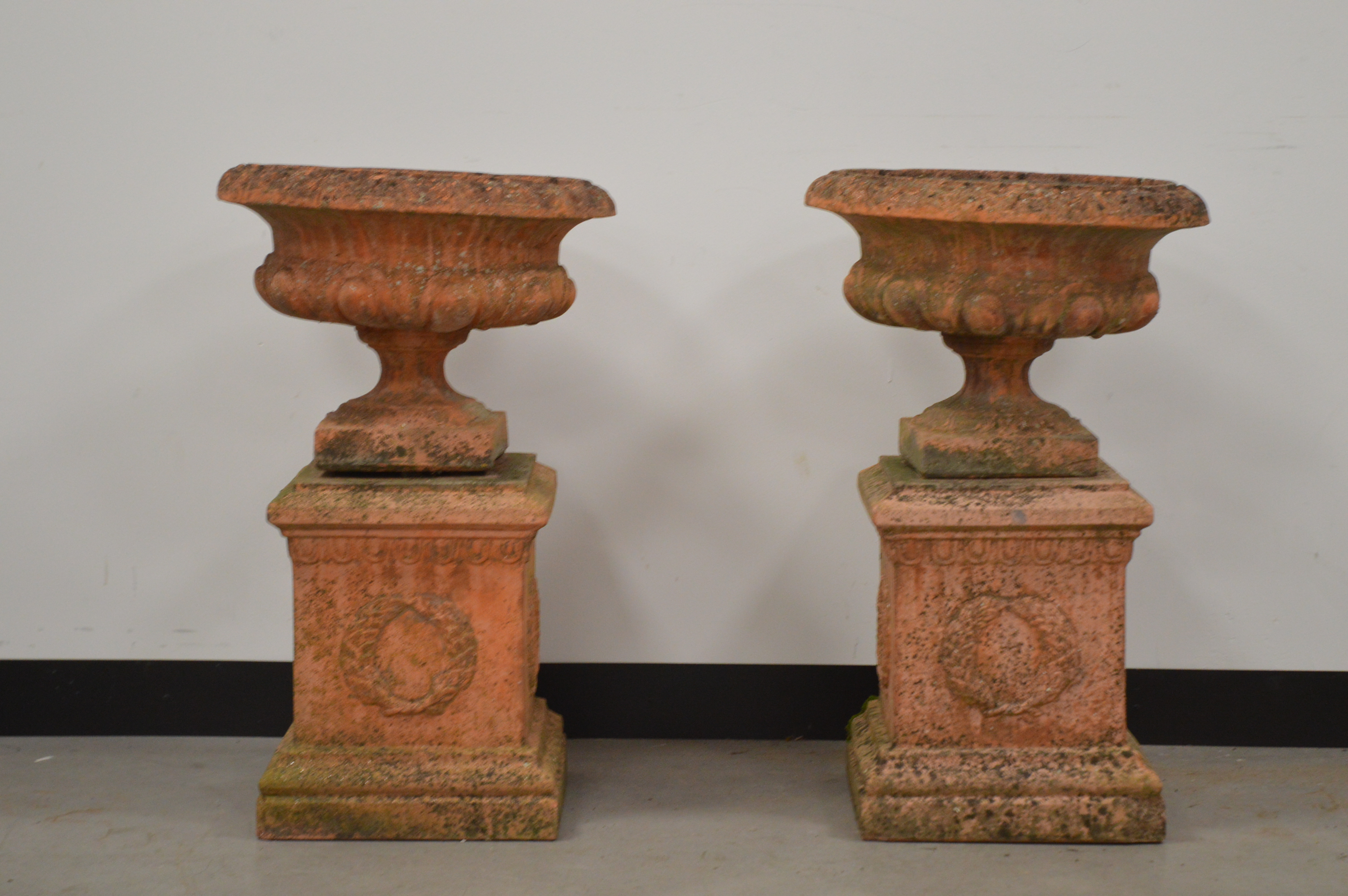 A pair of classical style garden urns on square bases, 73 cm tall. Some wear and weathering. AF (2)